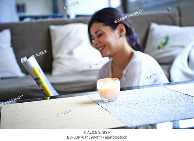 Woman reading near a scented candle