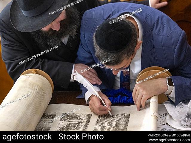 09 October 2023, Saxony-Anhalt, Halle (Saale): Rabbi Rachamim Havi (r) writes a Torah in the synagogue in Halle/Saale and is observed by Rabbi Elisha Mendel...