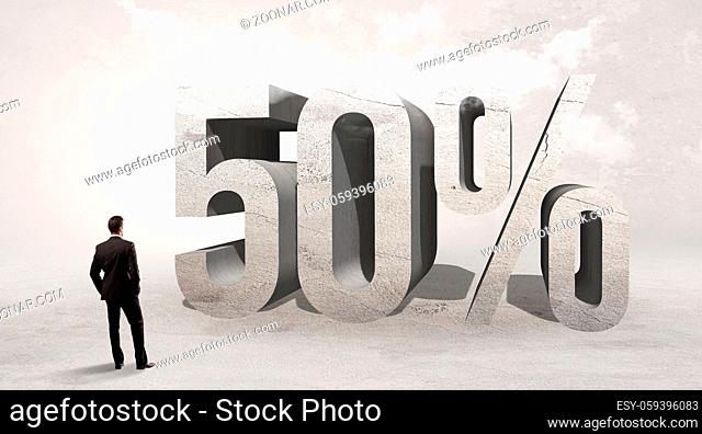 Rear view of a businessman standing in front of 50% abbreviation, attention making concept