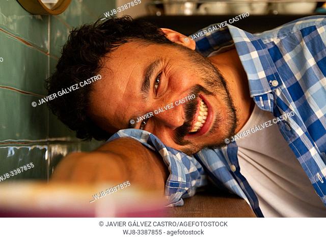 Young man leaning on a coffee shop table smiling
