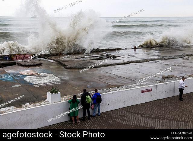 RUSSIA, SOCHI - NOVEMBER 13, 2023: People watch as waves smash against the coast during a storm on the Black Sea, in the Adler neighbourhood