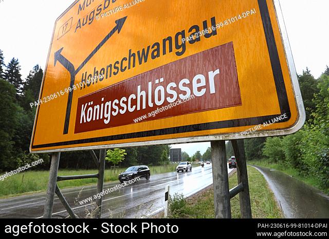 16 June 2023, Bavaria, Schwangau: Cars drive under a sign for the royal castles near Hohenschwangau. A man pushed two female tourists into a ravine near...