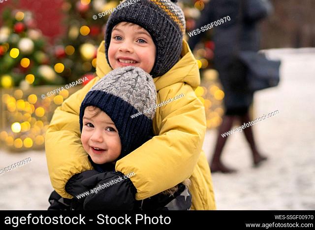 Smiling brothers embracing at Christmas market