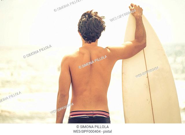 Back view of young man with surfboard