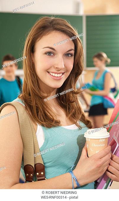 Germany, Emmering, Teenage girl smiling with students in background