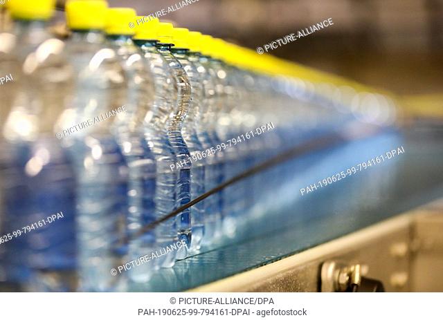 24 June 2019, Saxony, Eilenburg: Bottles of Ileburger mineral water with lemon taste run through the filling plant at Sachsenquelle GmbH