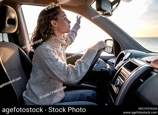 Young woman sitting on driver's seat in car