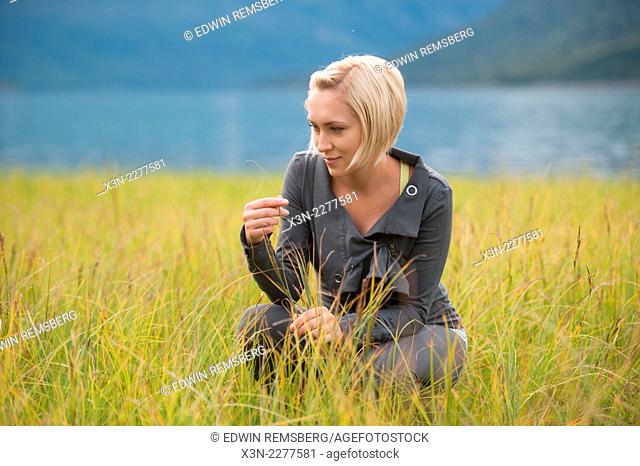 Woman examines marsh grasses by lake Eklutna Alaska