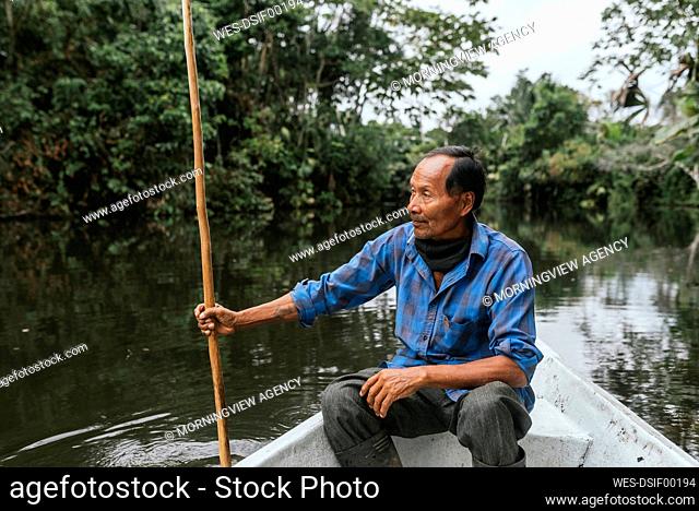 Senior Guarani man sitting in canoe at Napo River, Ecuador