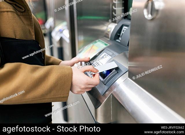 Woman using credit card on ticket machine at station