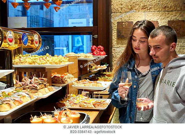 Young couple eating "Pintxos" at the Meson Portaletas, Parte Vieja, Old town, Donostia, San Sebastian, Gipuzkoa, Basque Country, Spain