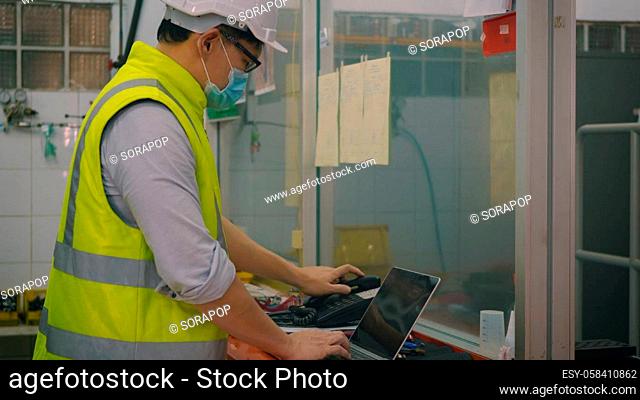 Asian factory worker man offering phone receiver as business communication, Technician man helmet at work in control room station talking on telephone