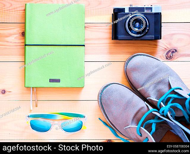 Set of travel and resort stuff. Camera, note book, sun glasses and deserts on wooden table. Top view, flat lay
