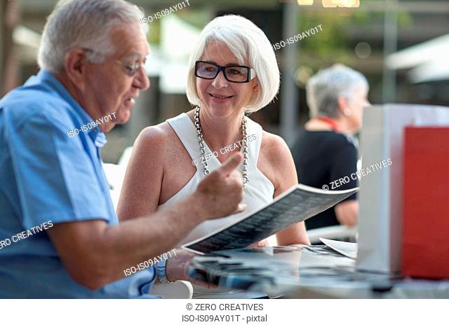 Senior man and woman reading menu at sidewalk cafe