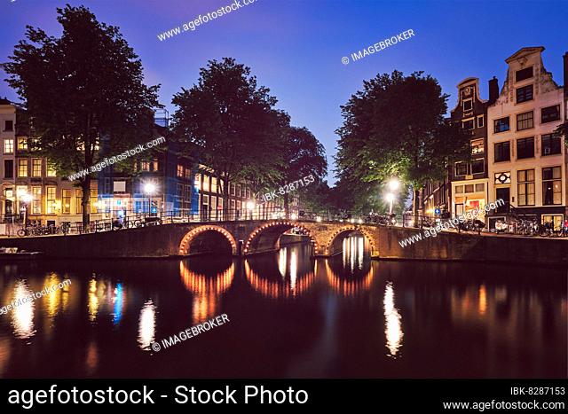 Night view of Amterdam cityscape with canal, bridge and medieval houses in the evening twilight illuminated Amsterdam, Netherlands