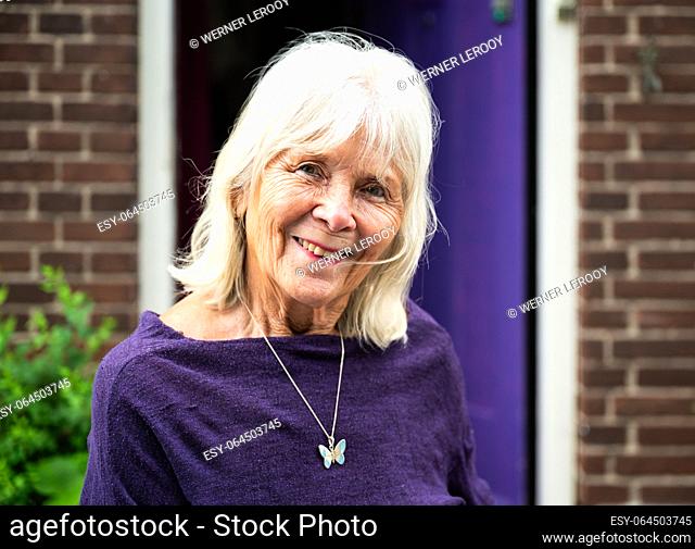 Rotterdam, South Holland, The Netherlands, July 4, 2023 - Portrait of a cheerful 82 yo senior lady with a purple background
