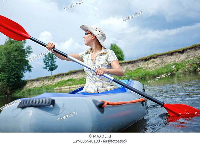 Happy woman paddling a kayak on the river, enjoying a lovely summer day