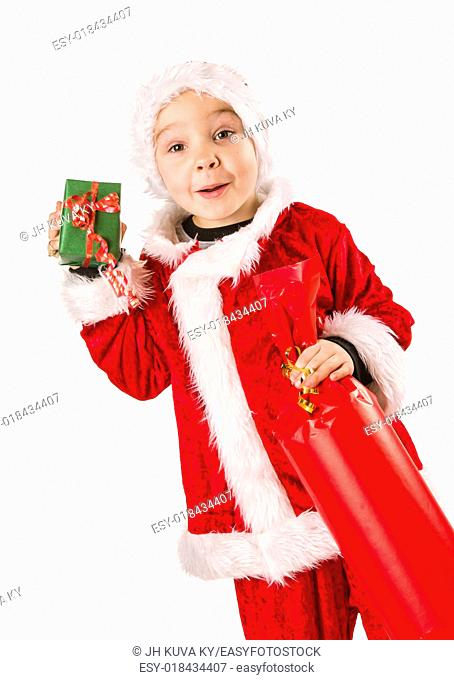 Smiling 5 year old boy wearing Santa Claus costume, Christmas gifts, white background