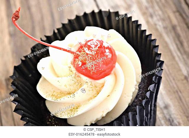 Close up of a cupcake with a red glased cherry on top
