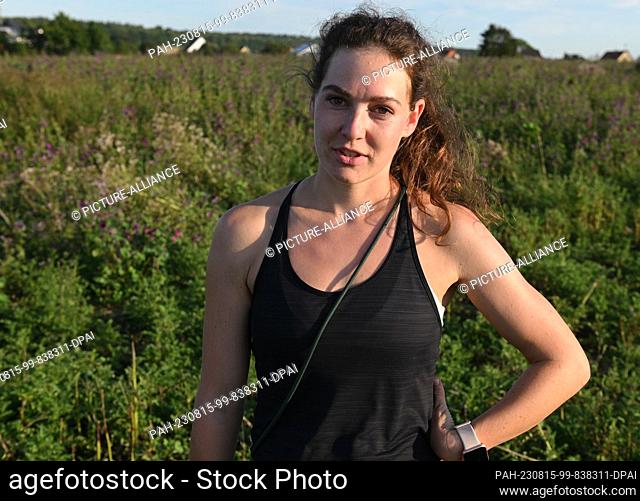 11 August 2023, Hesse, Kirch-Göns: Veterinarian Julia Heinze, supervisor in the Field Hamster Land project, stands in front of a wild herb flowering area with...