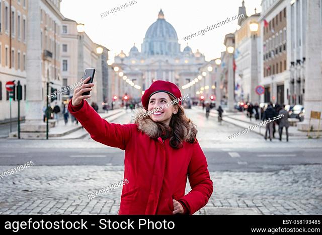 Girl in red dress and red beret takes a selfie with the background of St. Peter's Basilica in the Vatican