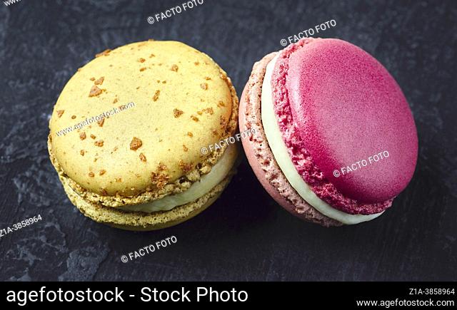 Two sweet French macarons on a dark background