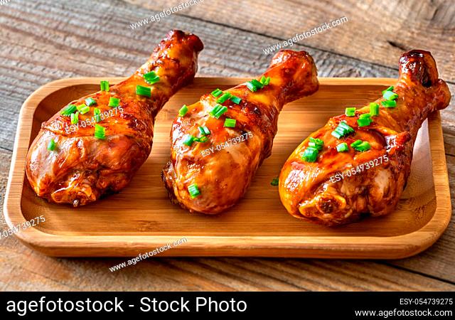 Grilled chicken drumsticks topped wih green onions on a serving plate