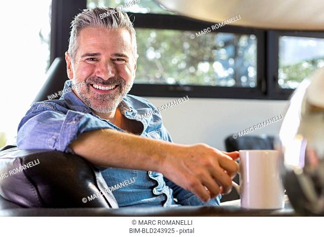 Caucasian man sitting on sofa and drinking coffee