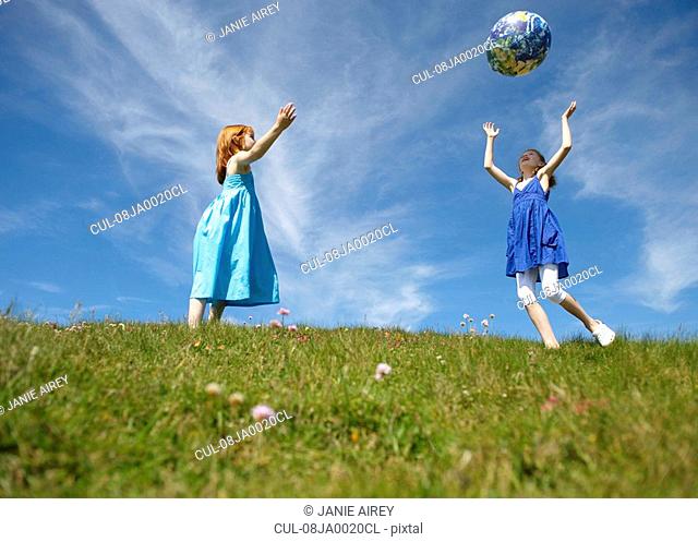 2 young girls throwing inflatable globe