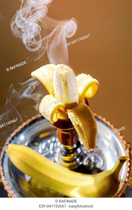 Smoking hookah with fruit head on dark background