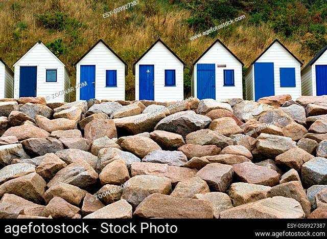 colorful row of small wooden beach cottages on the rocky Normandy coast in Barneville-Carteret