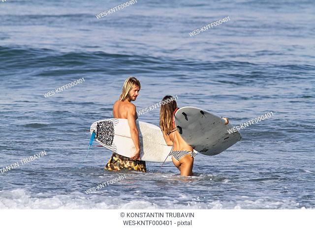 Indonesia, Bali, Surfer couple going into water