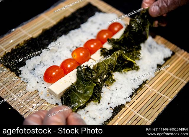 PRODUCTION - 07 November 2023, Lower Saxony, Oldenburg: A chef prepares sushi with kale, tomatoes and feta in the kitchen of the Moto Kitchen restaurant