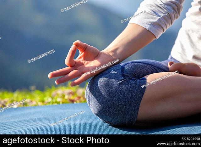 Close up of woman in Padmasana yoga lotus pose with chin mudra outdoors with copyspace