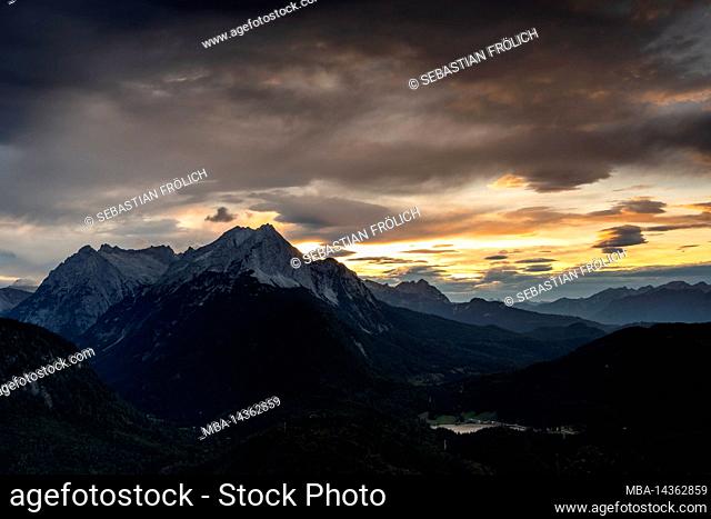 View from the Mittenwald hut of the Wetterstein mountains and the Lautersee lake near Mittenwald in the Bavarian foothills of the Alps in the evening red with...