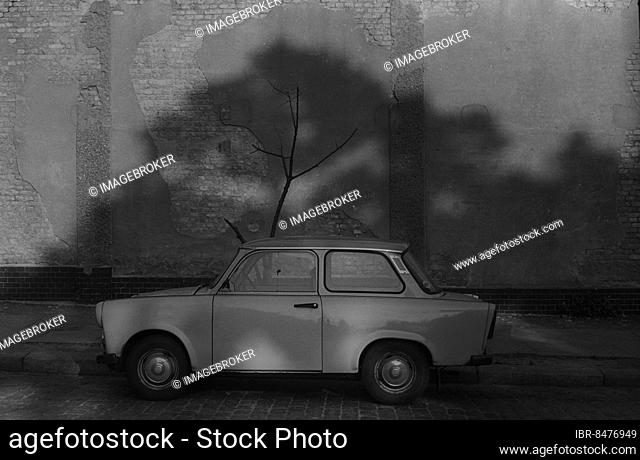 GDR, Berlin, 28. 07. 1986, Trabant (Trabi) in front of wall with tree shade, dead, withered tree