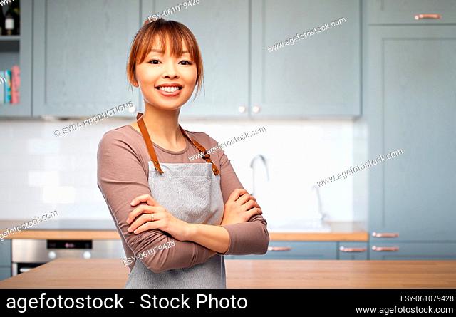 happy smiling woman in apron in kitchen at home