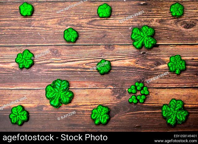 Glitter Covered Four Leaf Clovers for Saint Pattys Day in a Diagonal Pattern on a Wood Background