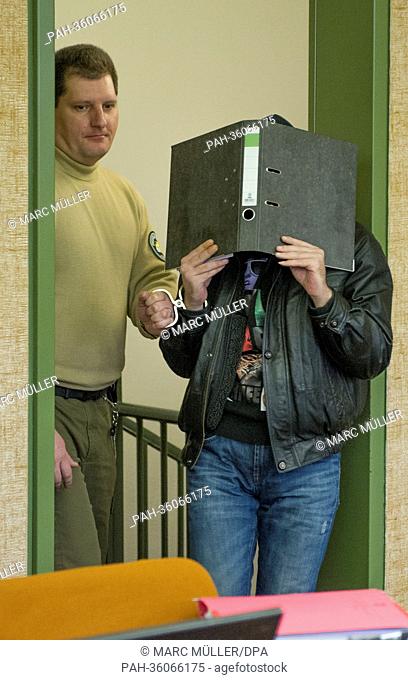 Defendant Andreas R. (R) covers his face with a binder as he appears at the Regional Court I in Munich, Germany, 09 January 2013. R