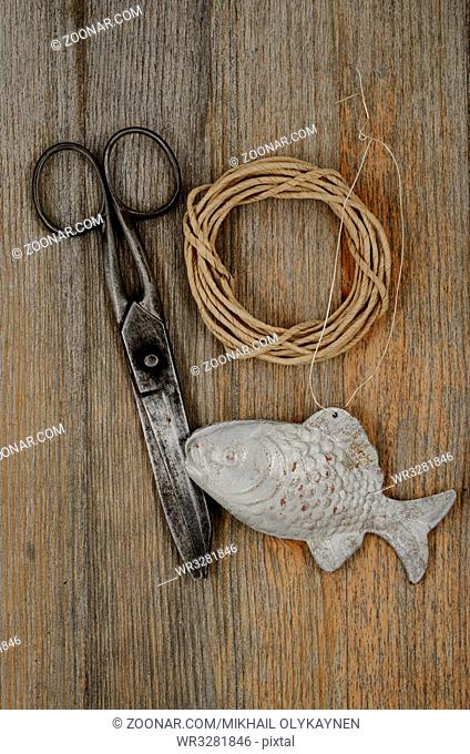 old scissors, glasses, fish and hank of packthread over wooden background