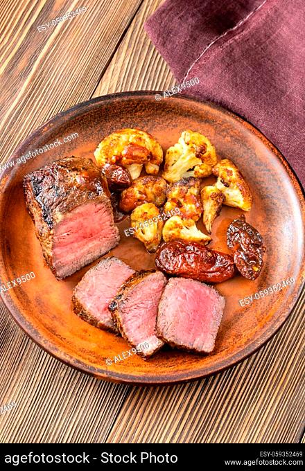 Grilled strip steak garnished with cauliflower and chipotle peppers