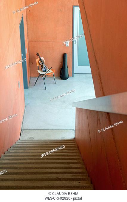 Violin, bow, sheet music on wooden chair and violin case leaning at wall
