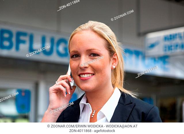 Eine Geschäftsfrau telefoniert mit ihrem Handy am Flughafen. Roaminggebühren bei Smartphones im Ausland
