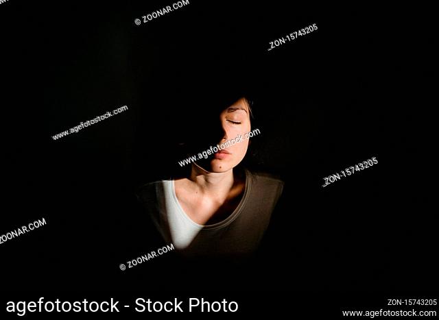 Girl sitting alone in sunlight pocket in dark room. mental health concept. High quality photo