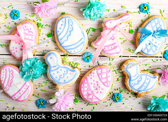 Easter frosted cookies in shape of egg chicken and rabbit on white wooden table background along with sugar sprinkles. Flat lay horizontal mockup