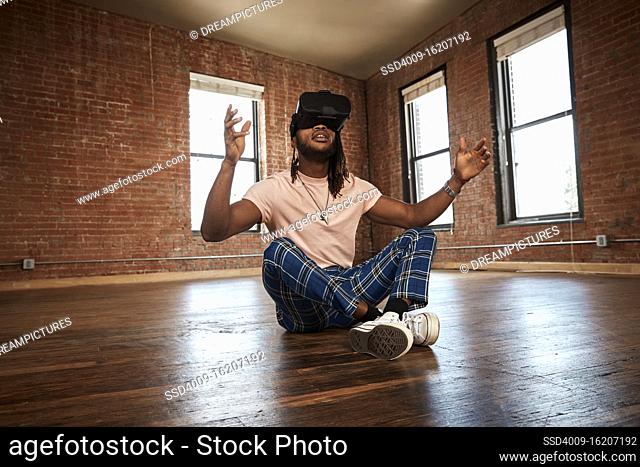 portrait of stylish young ethnic man wearing VR headset in empty loft space