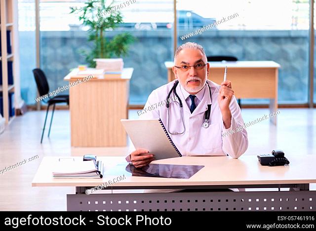 Old doctor taking notes in the clinic