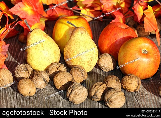 Apples, pears and wal nuts on a rustic wooden table as autumn motif