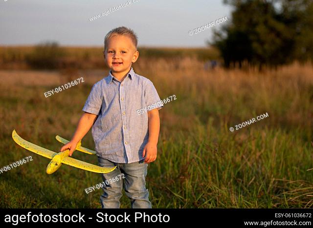 Little boy in the field plays with an airplane