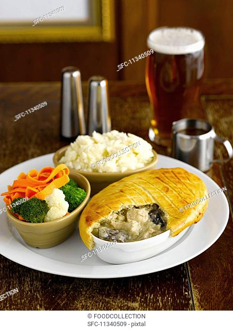 Chicken and mushroom pie with vegetables and mashed potatoes in a pub